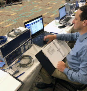 Dave Carter sits at a laptop connected to SEL equipment.