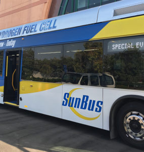 A hydrogen fuel cell "SunBus" sits outside a conference center.