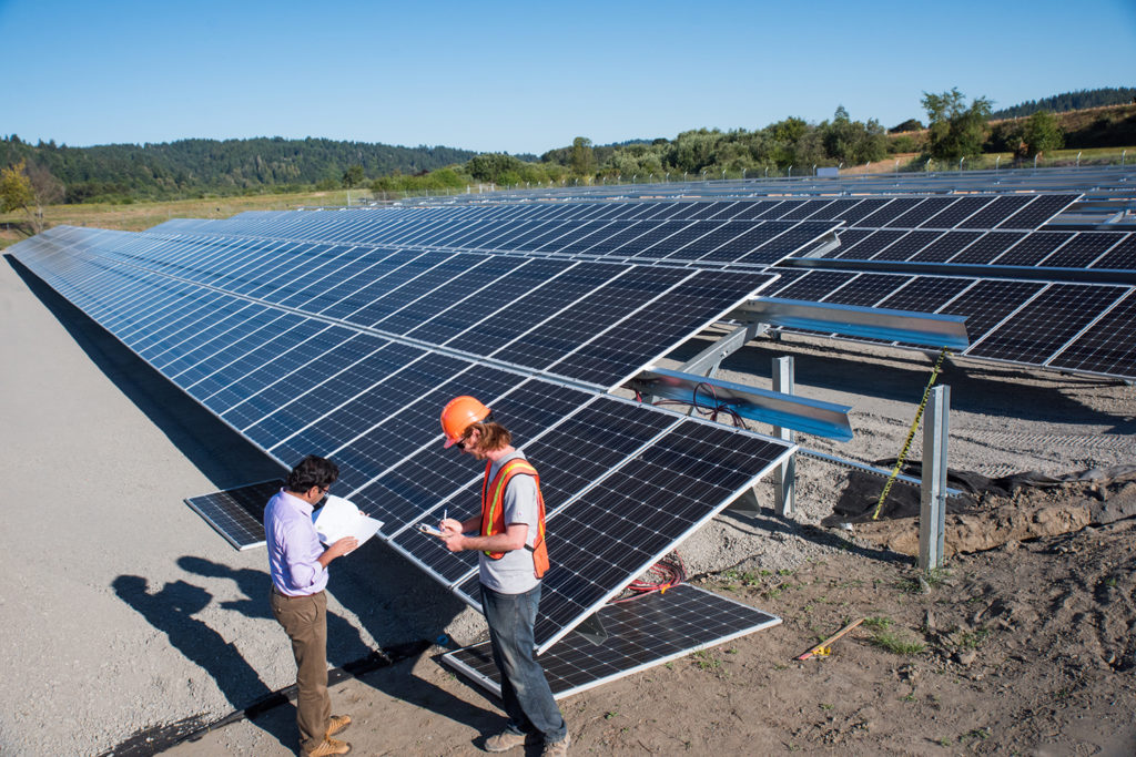 Two students refer to a blueprint at the Blue Lake Rancheria solar array.