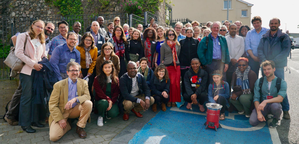 Roughly 50 participants pose for a photo in front of a cookstove