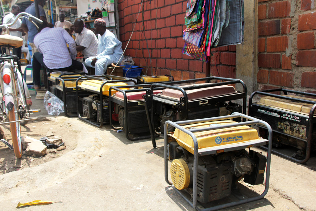 Men sit near an array of generators