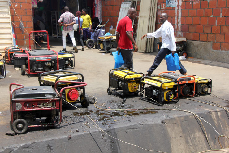 Men walk past an array of generators which are leaking fuel