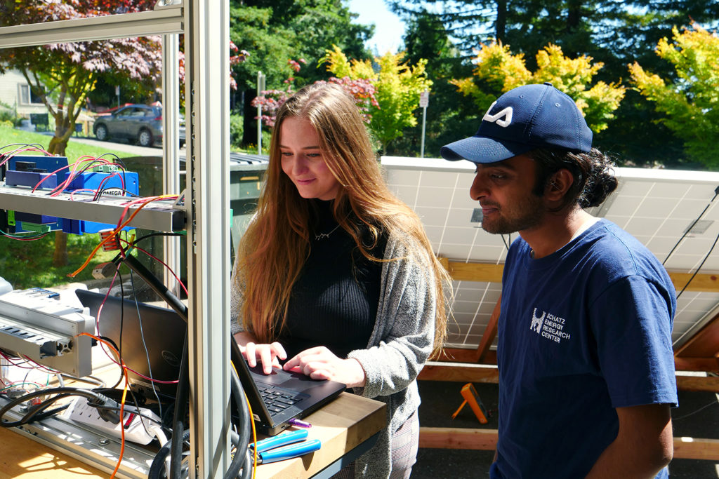 Two people measure the efficiency of a solar water pump