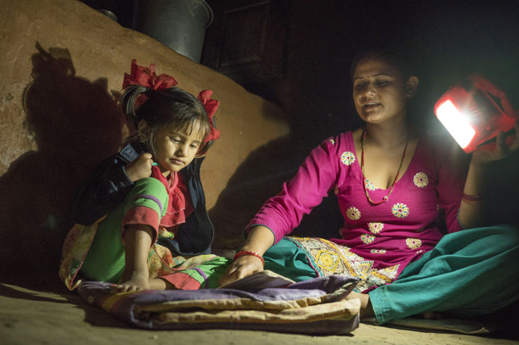 Ambika Parajuli holds a solar lamp to help her four year old daughter do homework.