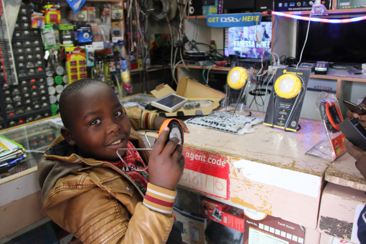 A child holds a solar product while standing at a store counter
