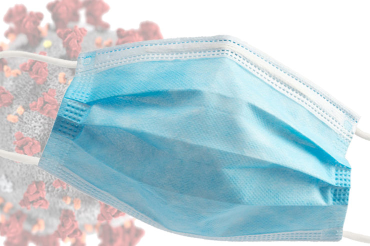 A blue surgical mask is superimposed over a graphic of a coronavirus