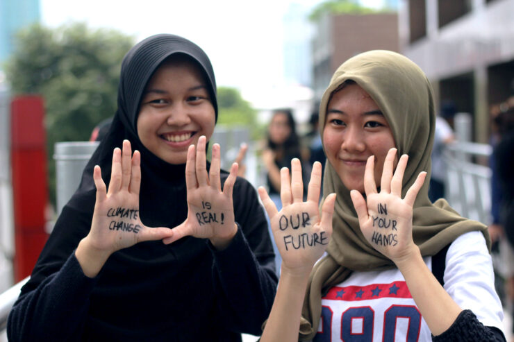 Two young women with "Climate Change is Real! Our future in your hands" written on their palms