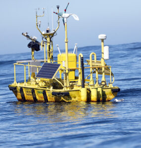 A yellow buoy with multiple sensors floats in open sea