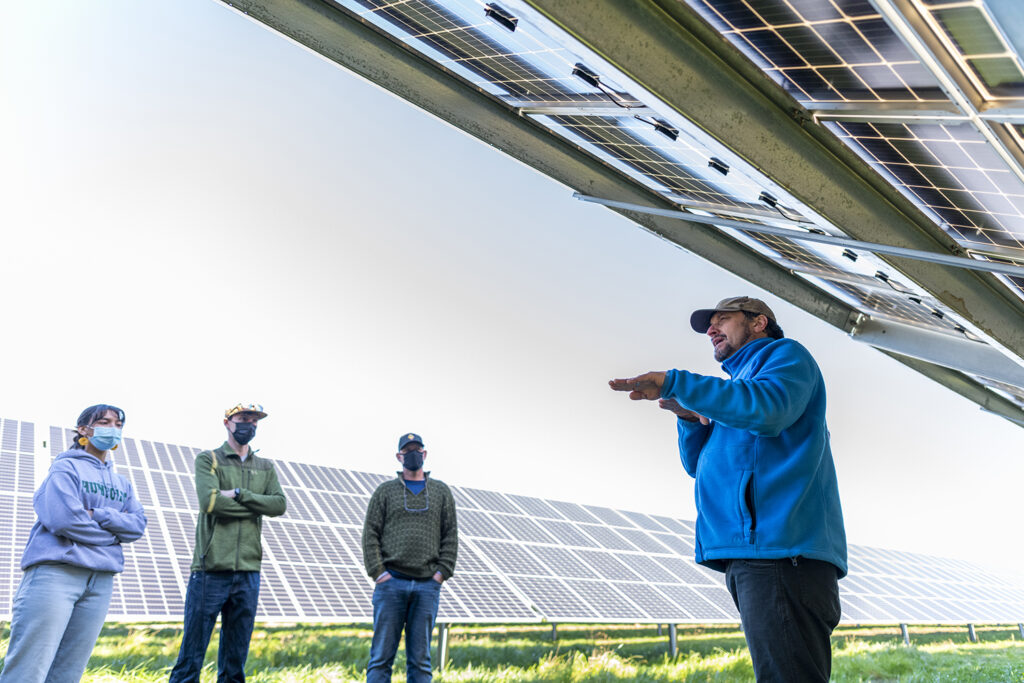 Four people stand in a solar array field