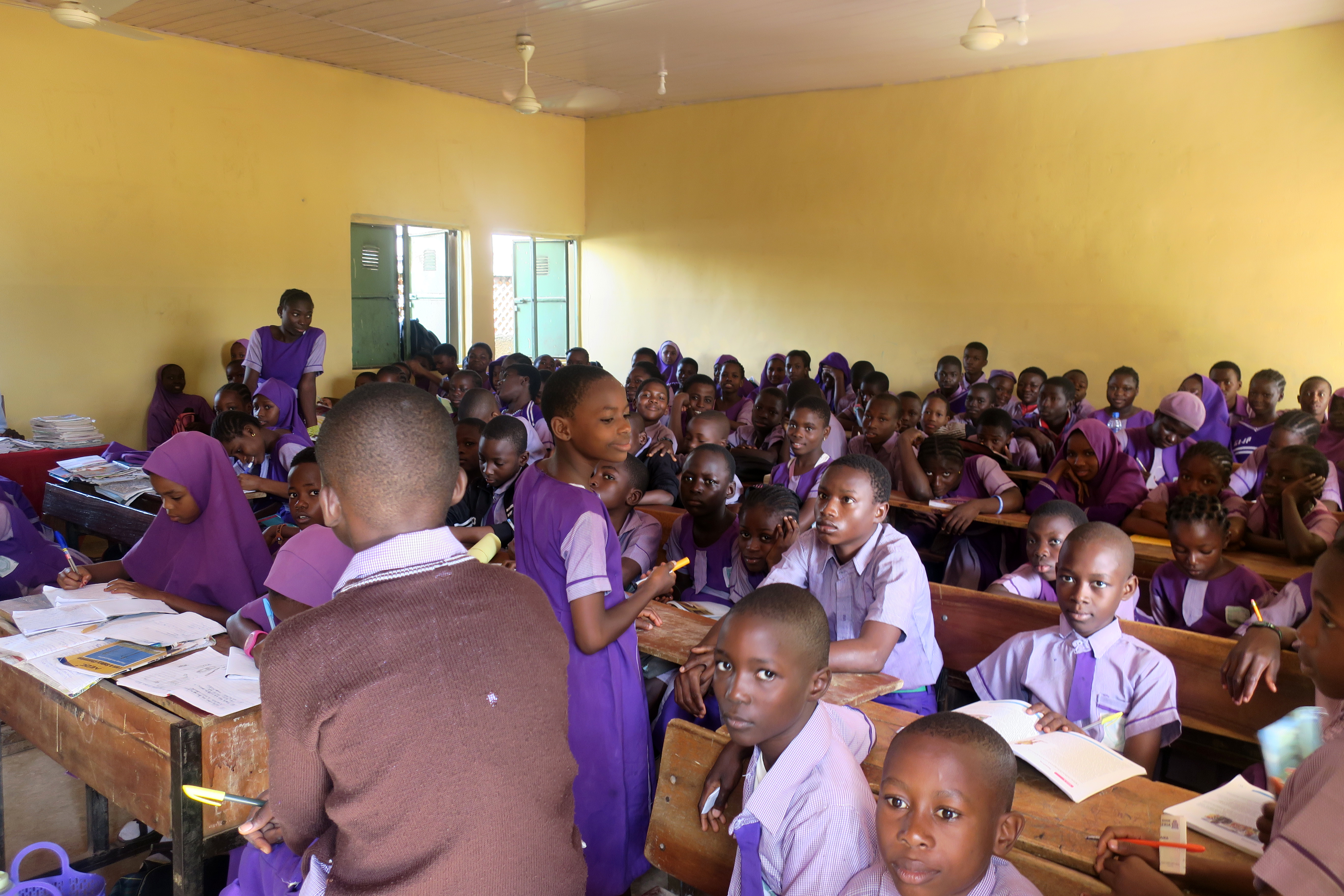 A full class of students works at their desks.