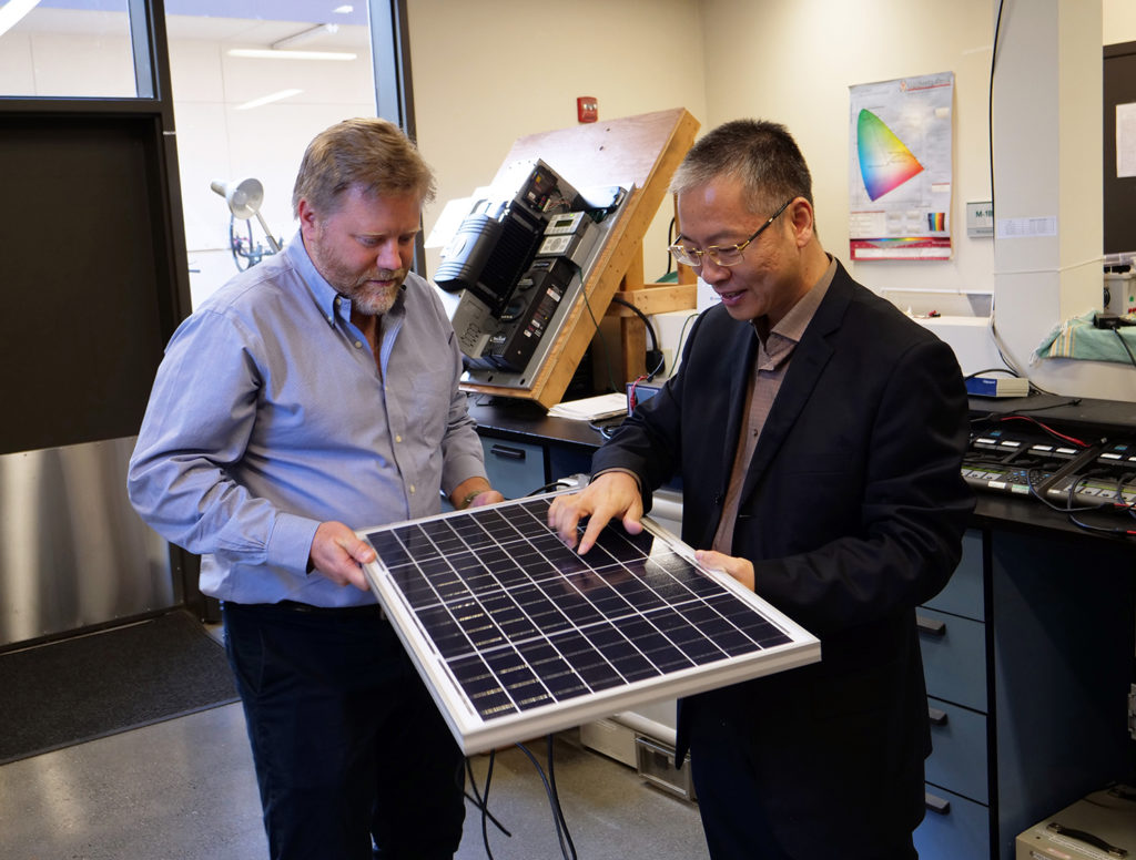 Arne and Honglin inspect a module in the Schatz Center's off-grid solar products test lab.
