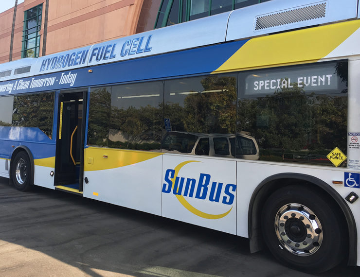 A hydrogen fuel cell "SunBus" sits outside a conference center.