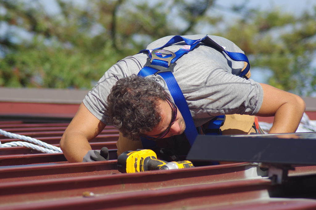 Marcelo bends close to the roof to view a connection