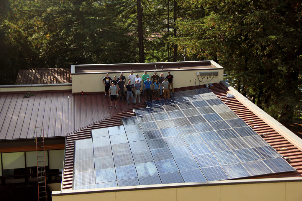 The installation team stands on the roof next to the assembled array