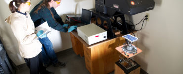 Two engineers use a solar simulator to test a solar module