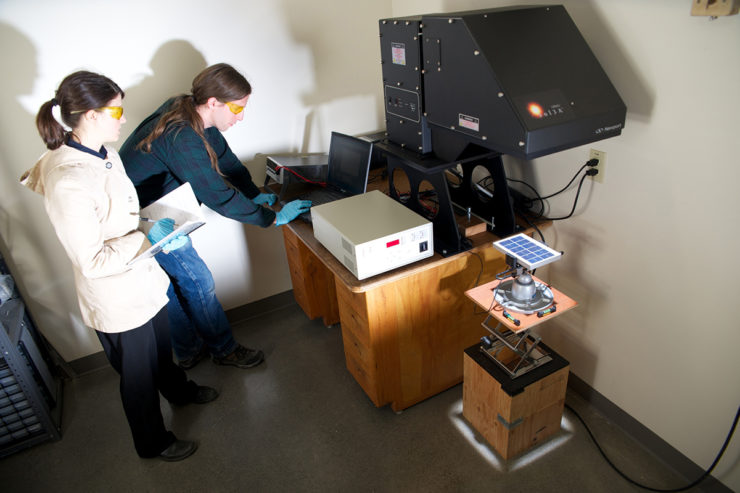 Two engineers use a solar simulator to test a solar module