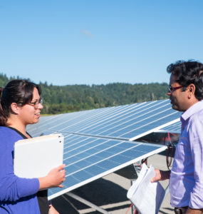 Two student observers stand at the foot of the array