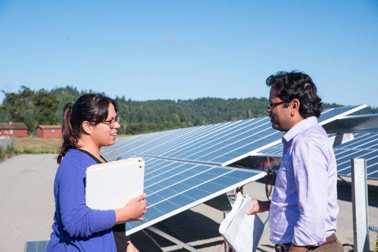 Two student observers stand at the foot of the array