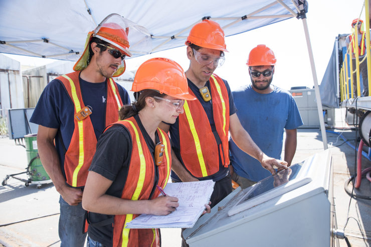 Students and staff in hardhats observe data from a torrefier