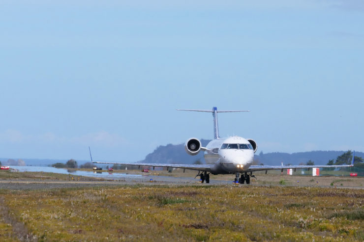 A plane moves along the runway, with Trinidad, CA in the distance