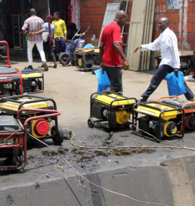 Men walk past an array of generators which are leaking fuel