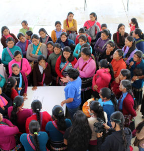 Over 50 women gather in a close circle to listen to a speaker